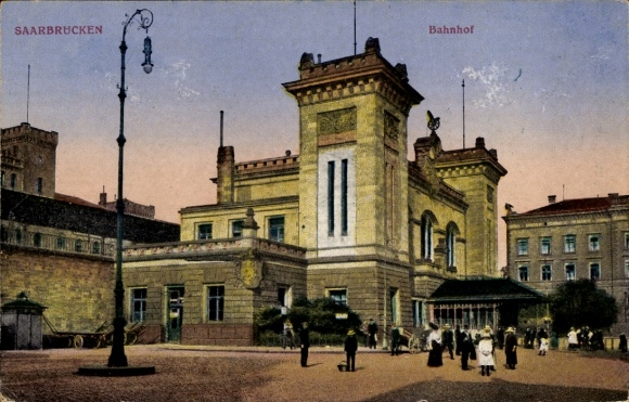 Ak Saarbrücken im Saarland, Bahnhof, historisches Gebäude, Menschen auf dem Platz, Laternen