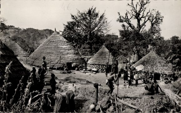 Ak Conakry Guinea, dorpsgezicht, traditionele hutten, mensen in traditionele klederdracht, landelijk tafereel