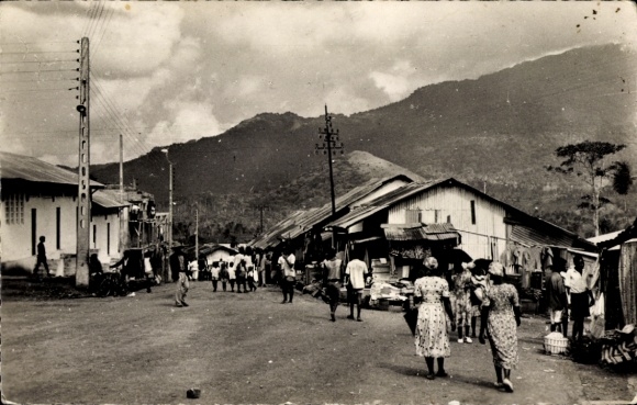 Ak Nkongsamba Kamerun, Straße mit Menschen, Häusern und Bergen im Hintergrund, Marktszene