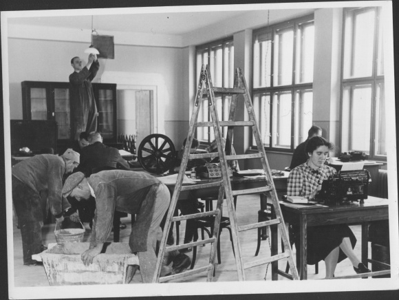 Photo interior of an office, woman at the typewriter, painter, ladder