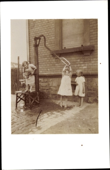 Photo Three girls are playing at the water pump