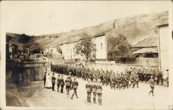 Photo Postcard German soldiers company at the battlefield, marching through a street, WWI