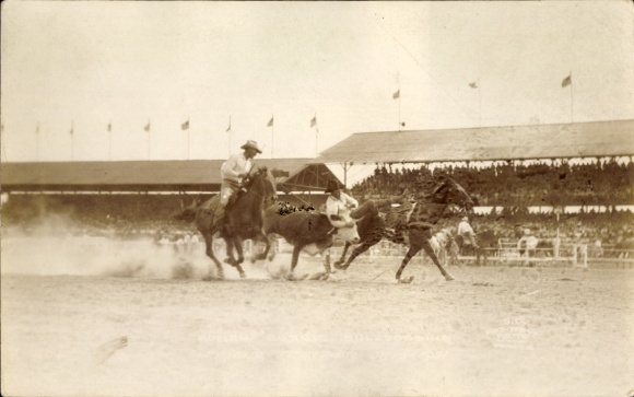 Photo Postcard USA, Two cowboys on horses, cow, spectator stands