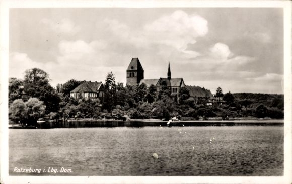 Ak Ratzeburg im Herzogtum Lauenburg, Dom und Gebäude am Wasser, bewaldete Umgebung, Wolkenhimmel
