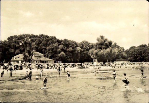 KP Ueckermünde w Pomorzu Zachodnim, plaża z kąpiącymi się, budynki w tle, drzewa, piasek