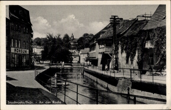 Ak Stadtroda in Thüringen, Kanal mit Häusern, Konsumgebäude, Brücke, ruhige Flusslandschaft