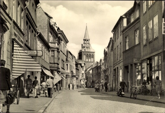 Postcard Güstrow in Mecklenburg, street with houses, people, bicycles, tower in the background