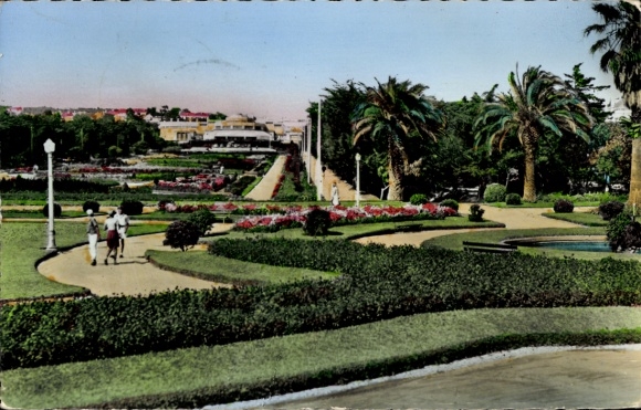 KP Cascaes Cascais Portugalia, piękny park, drzewa, kwietniki, spacerowicze, kasyno w tle