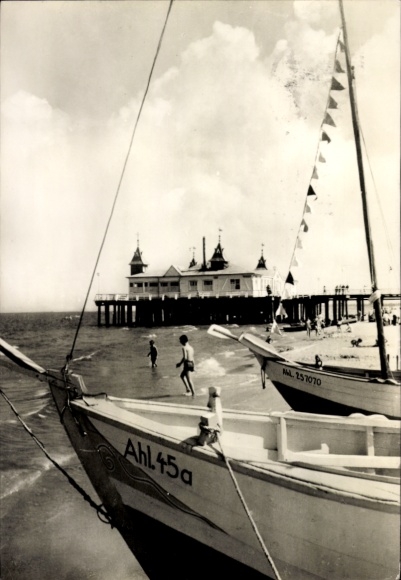 Postcard Ostseebad Ahlbeck on Usedom, pier with wooden walkways, boats in the foreground, colorful flags