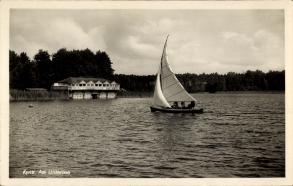 Postcard Kyritz in the Prignitz, lake with sailboat, shore house, cloudy sky