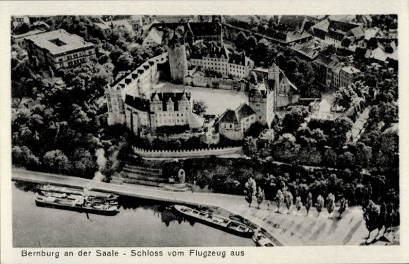 Postcard Bernburg an der Saale, aerial view of the castle, Saale, boats on the shore, wooded surroundings