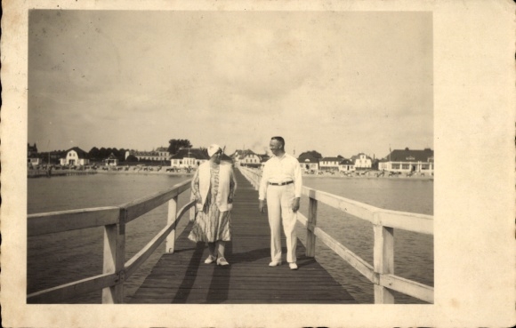 Postcard Ostseebad Dahme in Holstein, man and woman on a bridge, beach and buildings in the background