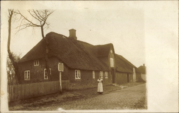 Photo Postcard Christian Albrechts Koog Galmsbüll in North Frisia, woman in front of a house with a thatched roof