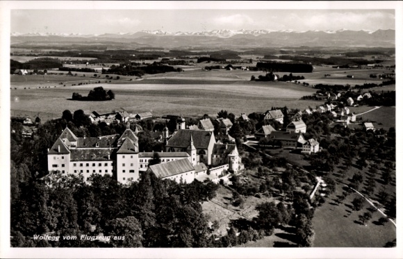 Ak Wolfegg im Allgäu, Luftaufnahme von  Schloss, Landschaft, Berge im Hintergrund