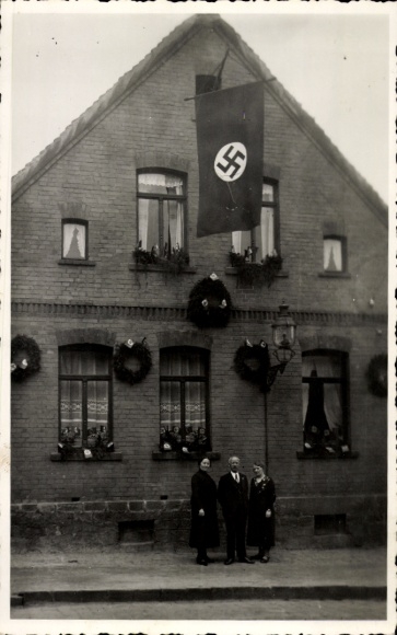 Foto Ak Helbra in Sachsen Anhalt, Familie vor einem geschmückten Haus, Fahne, Kränze