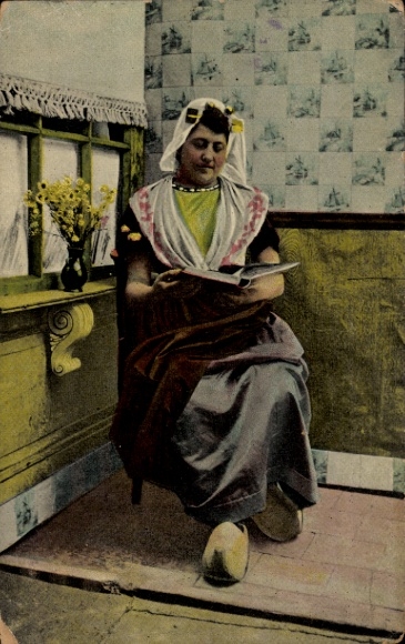 Postcard Netherlands, woman in traditional costume reading