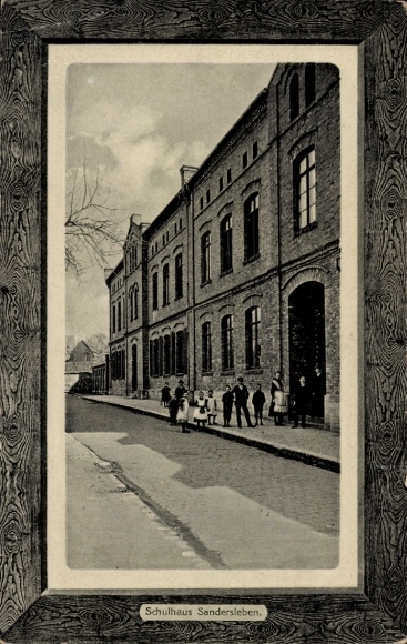 Ak Sandersleben in Anhalt, schoolgebouwarchitectuur, straat met mensen