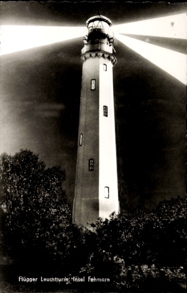Picture of a castle on the island of Fehmarn, Flügger lighthouse, night shot, rays of light, trees in the foreground...