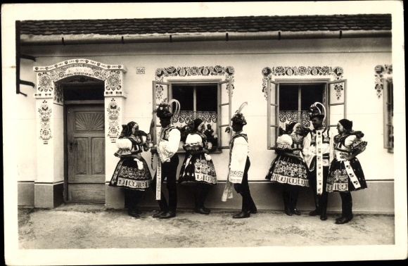Postcard Women and men in Slovak costumes, ornaments on house facades