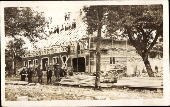Photo Postcard Construction workers in front of a construction site, building a house