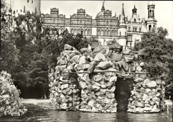 Ak Schwerin in Mecklenburg, Grotte aus Steinen im Wasser, Schloss im Hintergrund, Schwarzweißf...