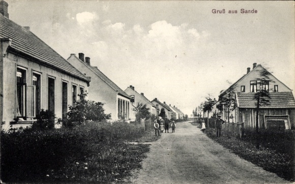 Postcard Sande in Friesland, depiction of a street, houses, clouds, people on the way