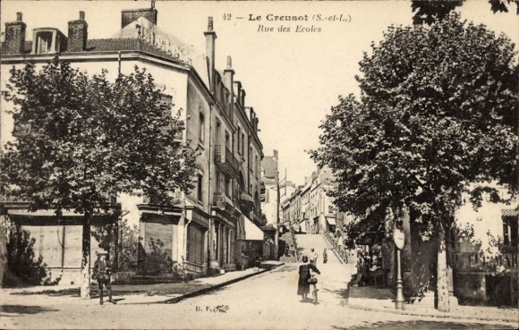 Ak Le Creusot Saône et Loire, Straße mit Bäumen, Häusern, Beschriftung Rue des Ecoles