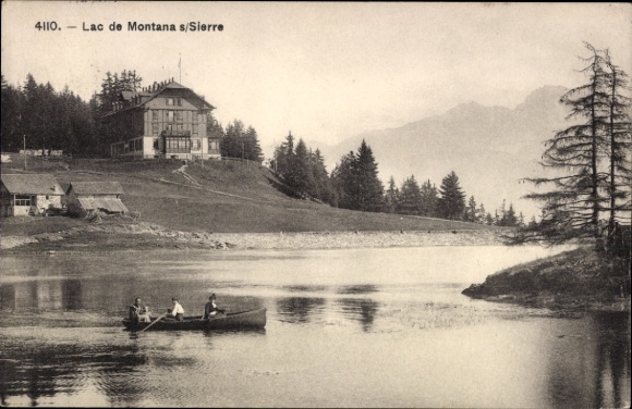 KP Montana Canton Valais, krajobraz z jeziorem, łodzią, drzewami, budynkami i górami w tle
