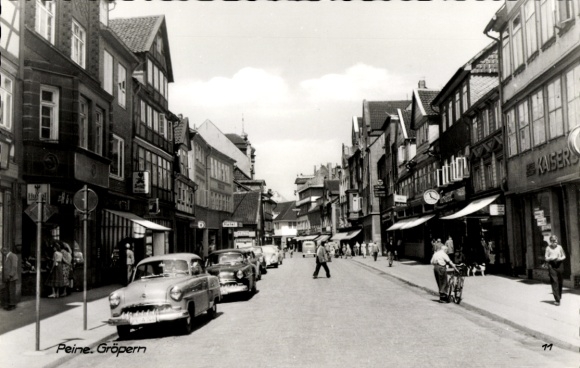 Postcard Peine in Lower Saxony, street in historic buildings, old cars, people on the street