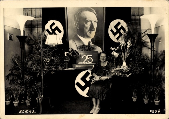 Photo of a woman with a bouquet of flowers in front of a Hitler portrait, 25th anniversary, August 21, 1942