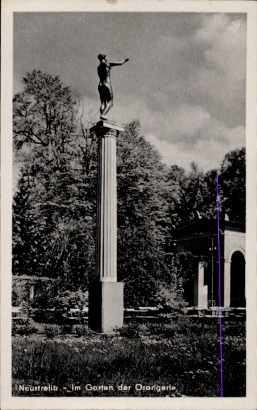 KP Neustrelitz w Meklemburgii, posąg na kolumnie, ogród oranżerii, czubki drzew, chmury