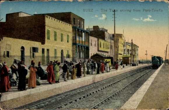 Postcard Suez Egypt, train station scene with waiting people, train on track, houses in the background