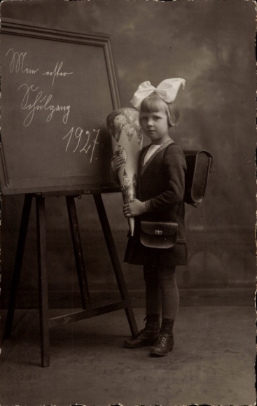 Photo Postcard Congratulations on starting school, girl with sugar bag and school bag in front of a blackboard 1927