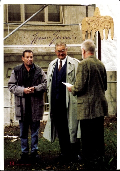 Postcard Burhave Butjadingen Wesermarsch, men stand in front of a sculpture. One holds a piece of paper...