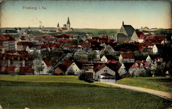 Ak Freiberg in Sachsen, Stadtansicht mit Gebäuden, farbenfroher Himmel, grüne Wiesen