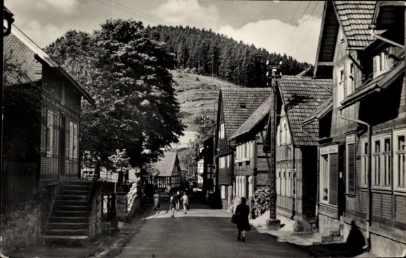 Picture of Gießübel in Thuringia, quiet street, half-timbered houses, trees, people, mountains in the background
