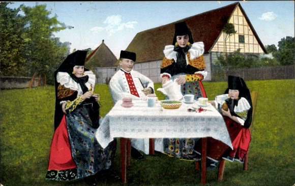 Postcard Bückeburg in the Schaumburg district, four people in traditional costumes sit at an outdoor table and...