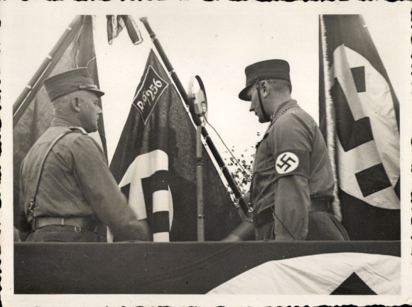 Photo SA men on a podium, microphone, standards