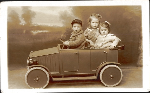 Foto Ak Kinder in Spielzeugauto, Junge und zwei Mädchen