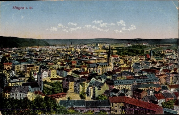 Ak Hagen in Westfalen, Stadtansicht, viele Gebäude, Hügel im Hintergrund, Wolken am Himmel