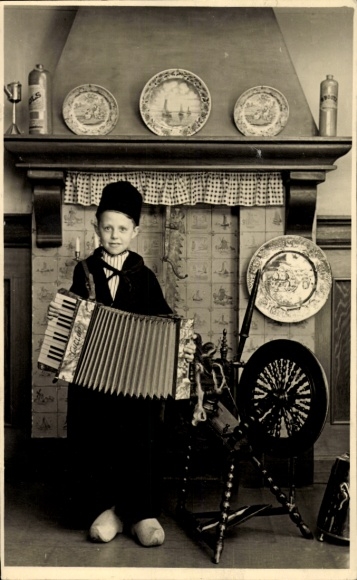 Foto Ak Portrait, Junge mit Akkordeon am Spinnrad
