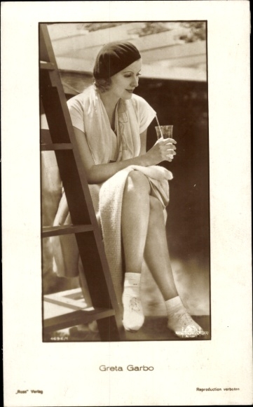Ak Schauspielerin Greta Garbo, Sitzportrait, Mütze, Glas