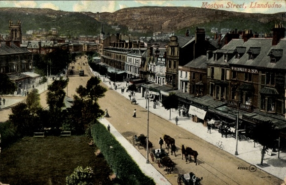 Postcard Llandudno Wales, Mostyn Street, shops, horse-drawn cart, mountain in the background