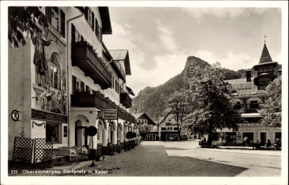Postcard Oberammergau in Upper Bavaria, village square, shops, mountains in the background