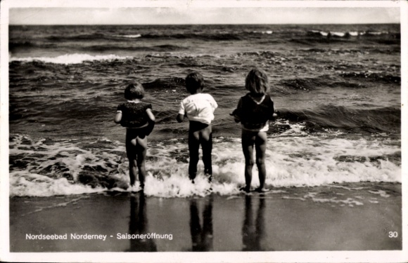 Postcard North Sea resort Norderney in East Frisia, season opening, children standing with bare bottoms by the sea