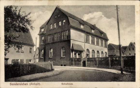 Ak Sandersleben in Anhalt, schoolgebouw, architectuur, straat, bomen