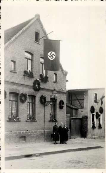 Foto Ak Helbra in Sachsen Anhalt, Familie vor einem geschmückten Haus, Fahne, Kränze