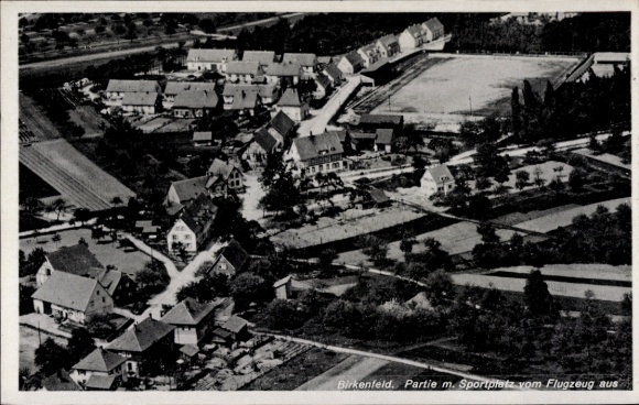 Postcard Birkenfeld an der Nahe, aerial view of residential buildings, sports field, rural surroundings