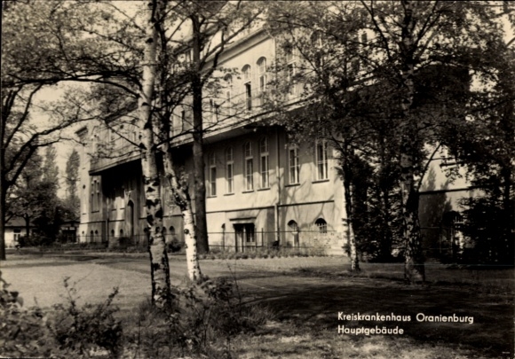 Postcard Oranienburg in Brandenburg, district hospital main building, trees in the foreground