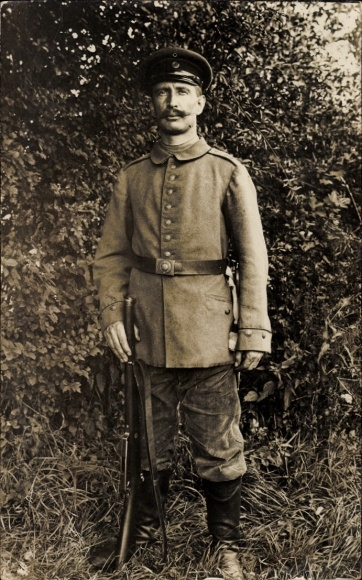 Postcard Westen Dörverden Lower Saxony, A soldier with a weapon stands in front of a bush.